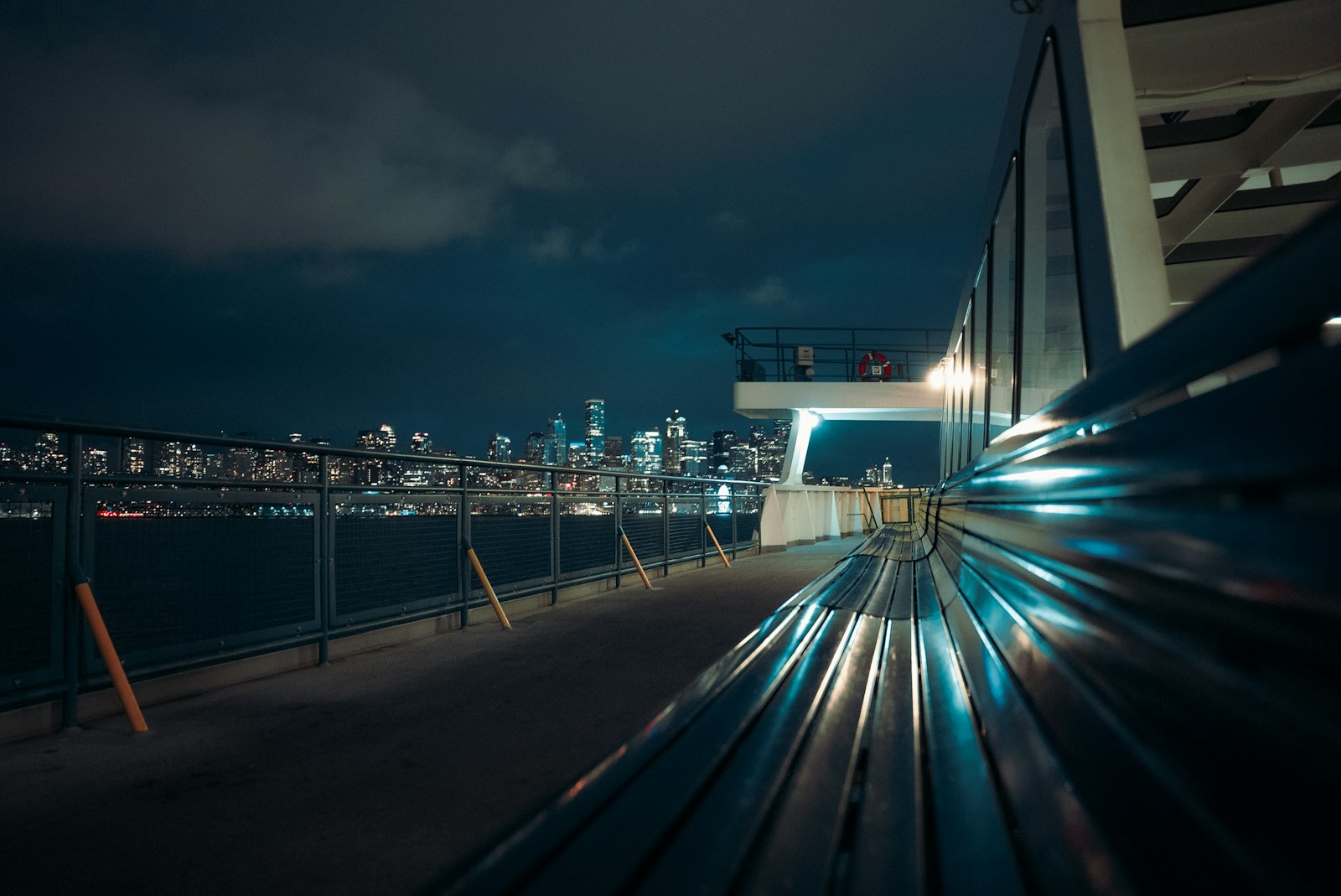 City skyline at night seen from a ferry deck.