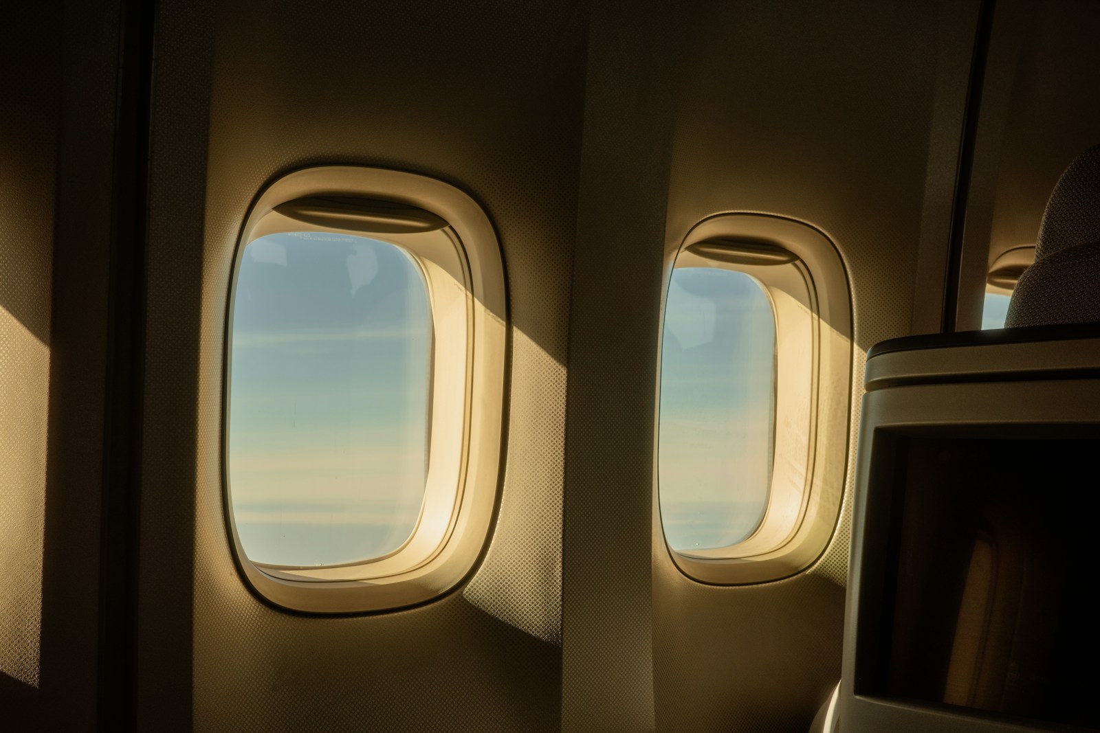 Sunlight streams through airplane windows overlooking clouds.