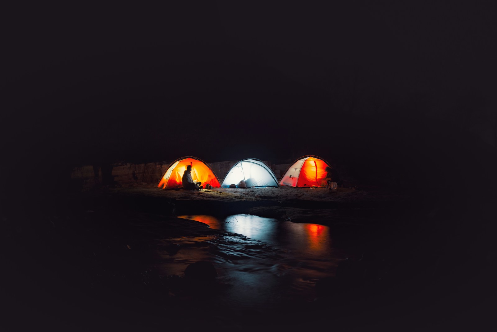 Three illuminated tents glowing in the dark night.